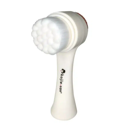 Une brosse nettoyante pour le visage Kojie San Brosse pour visage exfoliante pour peau parfaite blanche avec des poils doux et la marque « kojie.san » sur le manche. dakar