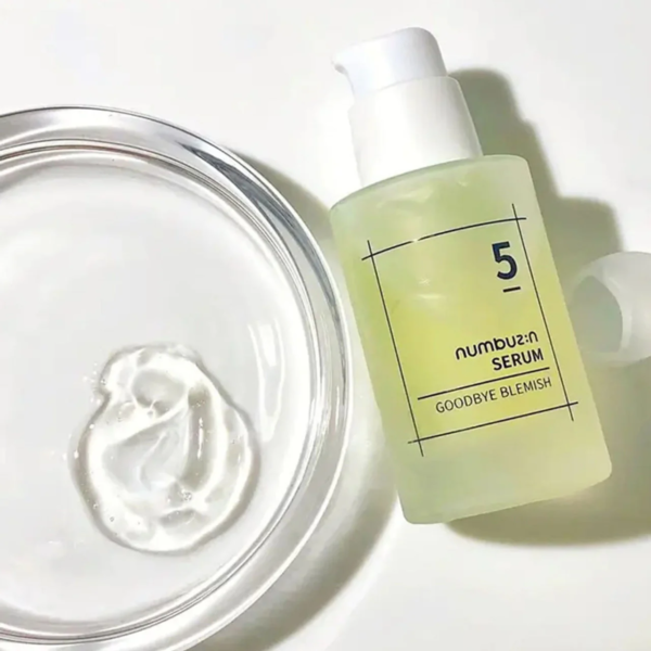 Un flacon de « Numbuzin Sérum Éclat Anti Imperfections Goodbye Blemish 50 ml » est posé à côté d'un plat contenant une petite quantité de crème