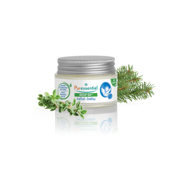 Un pot de Baume de massage pectoral Bébé Respire Bien 30 ml de Puressentiel est présenté à côté d'herbes vertes fraîches et de branches de pin. L'emballage est blanc avec des touches de vert et comprend une illustration de bébé bleue, avec le reflet du pot visible en dessous. Dakar