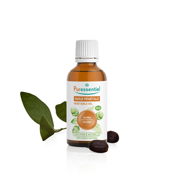 Un flacon de Puressentiel Huile Végétale Bio Jojoba 50 ml avec des feuilles vertes et des graines de jojoba à côté.