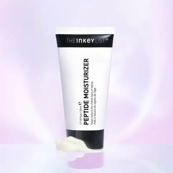 Un tube de THE INKEY LIST Crème Hydratante Raffermissant aux Peptides 50 ml avec une petite quantité de crème à côté sur un fond violet doux. dakar